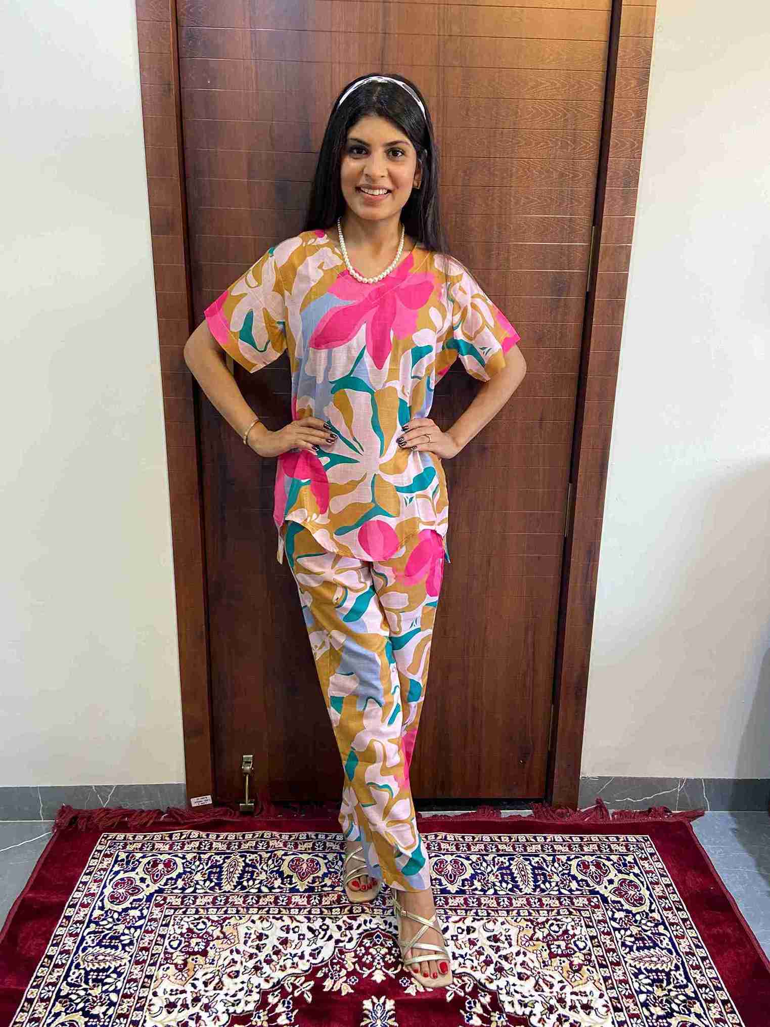 WhatsApp Image 2025-06-03 at 4.38.28 PM (1)_1_11zon Woman wearing a colorful floral cotton co-ord set featuring pink, mustard, and blue abstract prints, standing indoors on a red and navy patterned rug